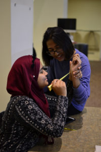 Vice President of the Muslim Student Association, Sinthia Shabnam gives classmate Soho Raja a henna tattoo at the Islam Fair on Tuesday Oct 24, 2017.