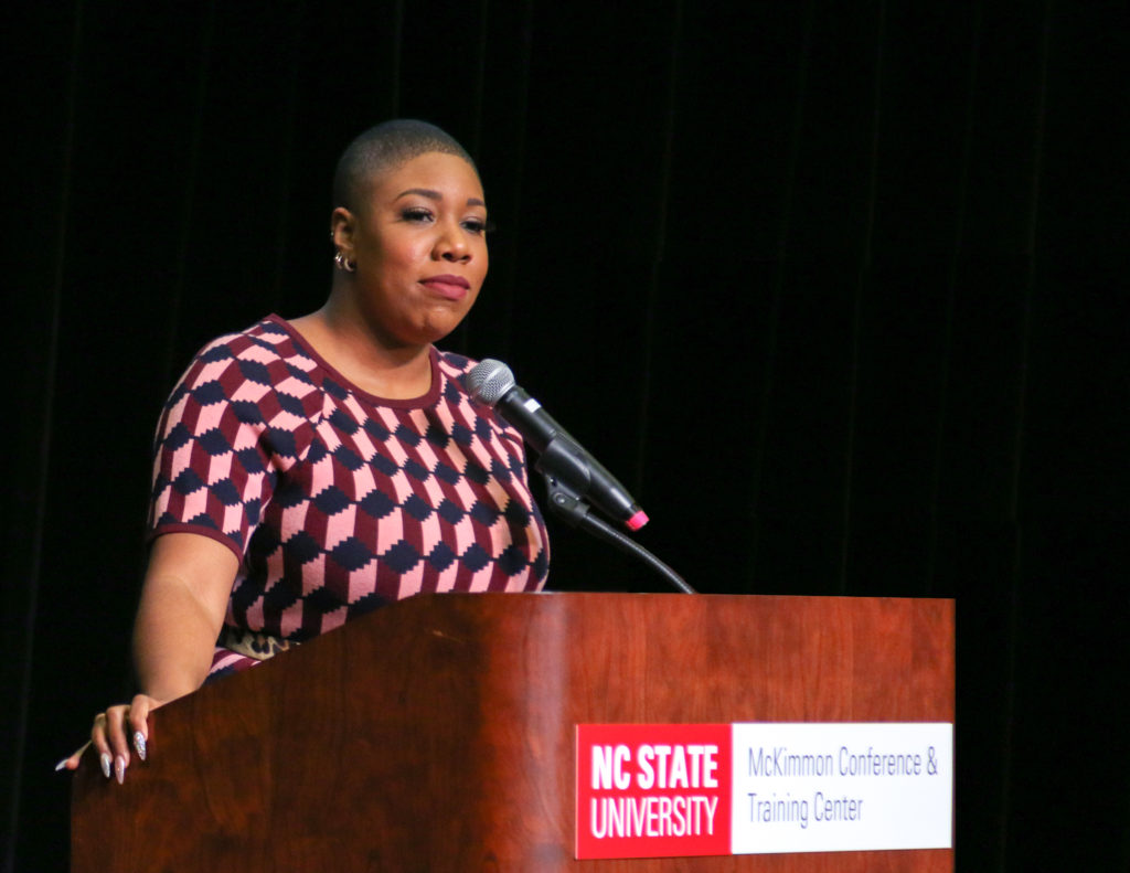 Symone Sanders stands at a podium in McKimmon Center to deliver the MLK Campus Commemoration speech.