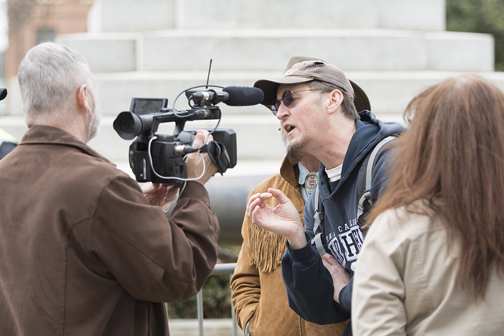 Michael, a anti-Confederate protester, interrupts an interview with a local news outlet and an Heirs to the Confederacy counter-protester. (Kaydee Gawlik/Nubian Message)
