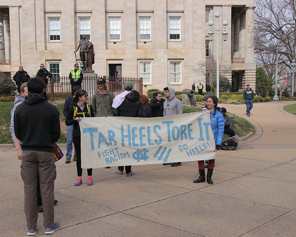 Protesters hold up a sign at the Crush Confederates at the Capital event on Saturday, Feb. 9 at the North Carolina State Capitol in Raleigh. The sign was up for a short time before on site officers requested its removal to comply with city ordinance laws. (Aditya Penumarti/Nubian Message)