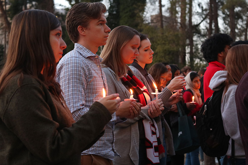 Students hold candles to honor the victims of the shooting in New Zealand.